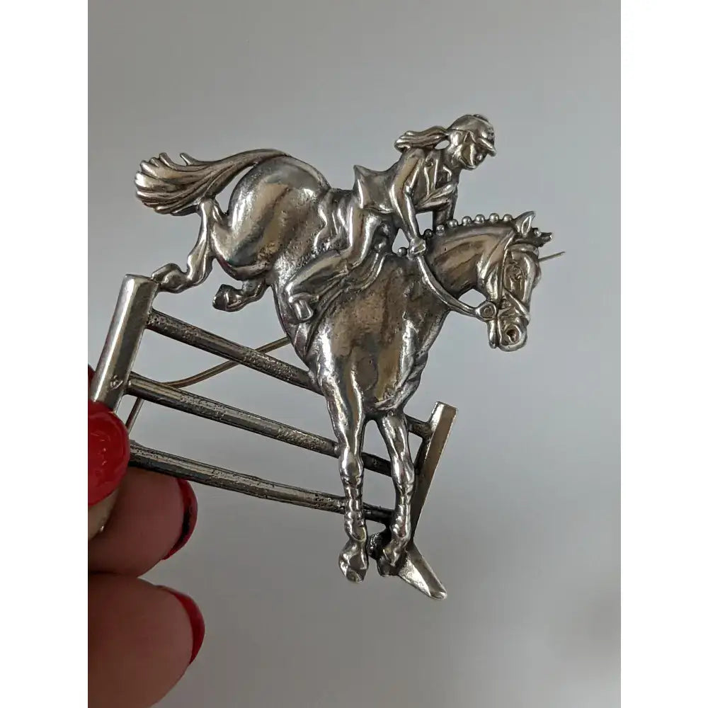 Silver steed triple bar jump jumping brooch in silver showing rider and horse mid-jump stock tie pin design