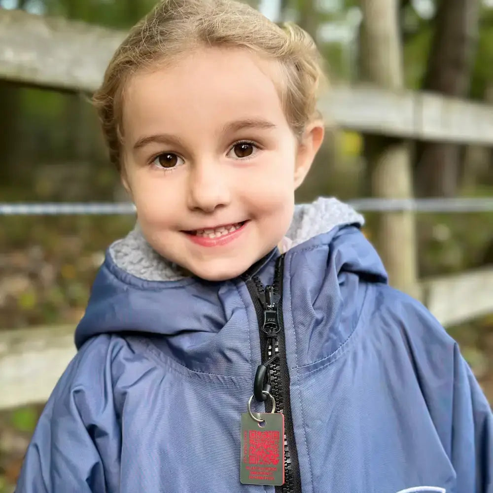 Blue hooded jacket with gray fleece lining and black zipper pull featuring a red rider emergency tag for young riders