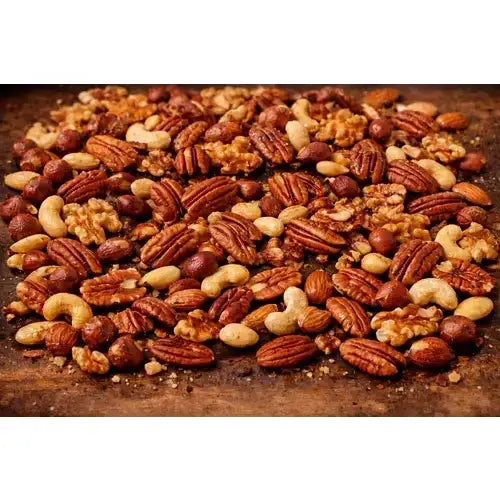 A generous pile of smoky sam’s honey roast hickory smoked nuts with pecans cashews walnuts and hazelnuts on wood