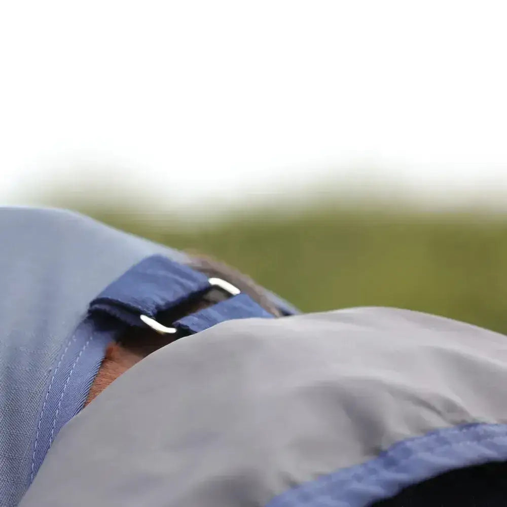 Blue fabric strap with silver buckle on gray stormx empra aqua shield fly rug for secure fit and durability
