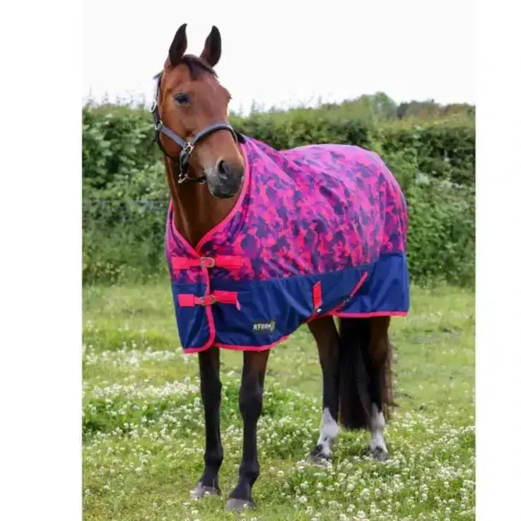 A vibrant pink and navy stormx original dynaforce 100g turnout rug with camouflage pattern and bright red straps