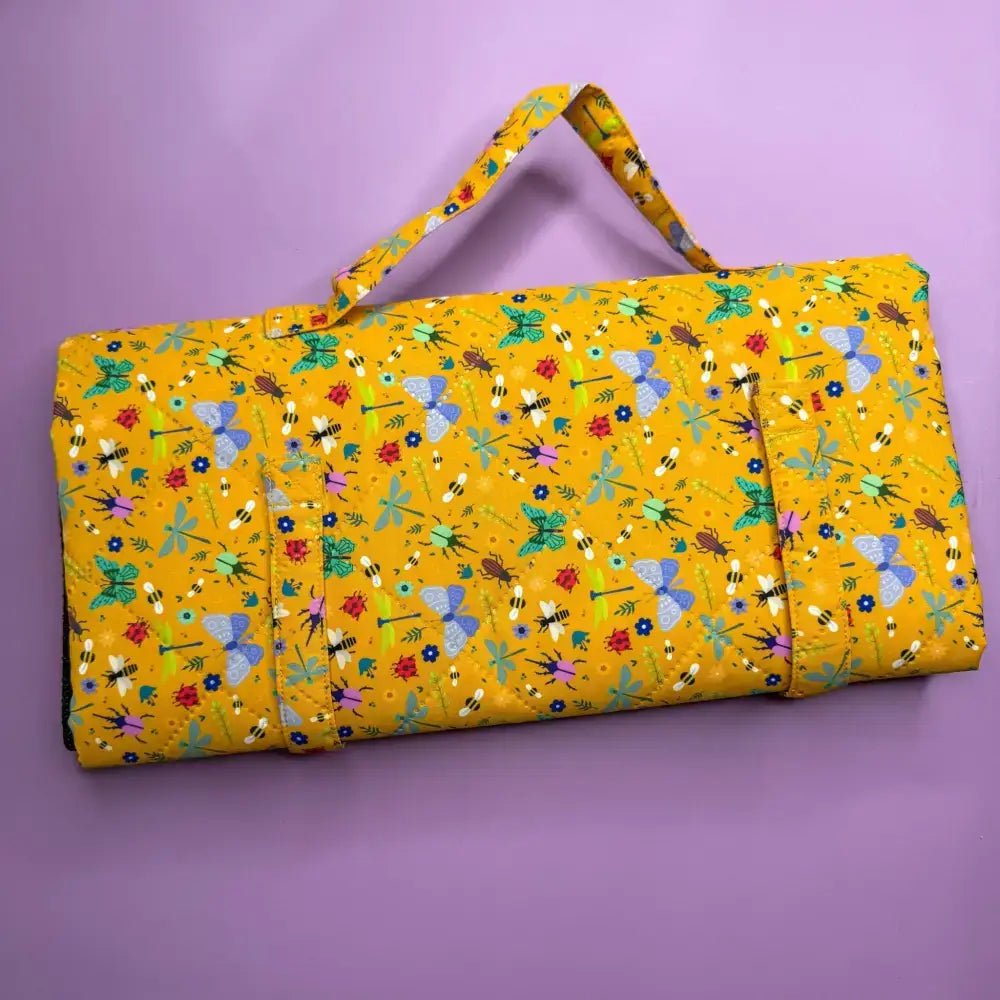 A vibrant yellow lightweight waterproof summer buzzin dog settle mat with bees butterflies and flowers pattern