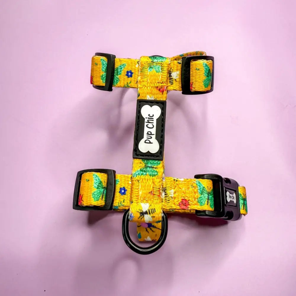 A vibrant yellow floral summer buzzin puppy strap harness with black buckles and bone-shaped tag for teacup puppies