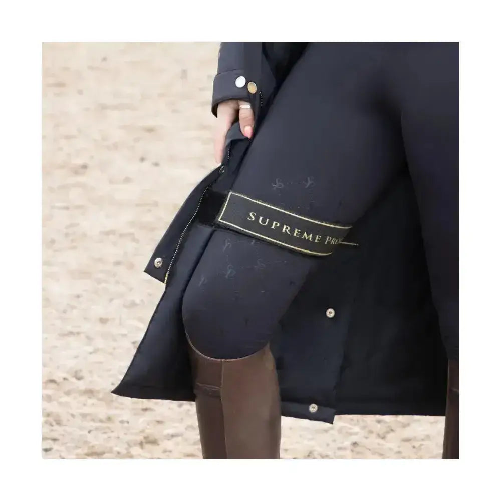 Black supreme products active rider waterproof coat with gold-tone buttons and branded label on the sleeve