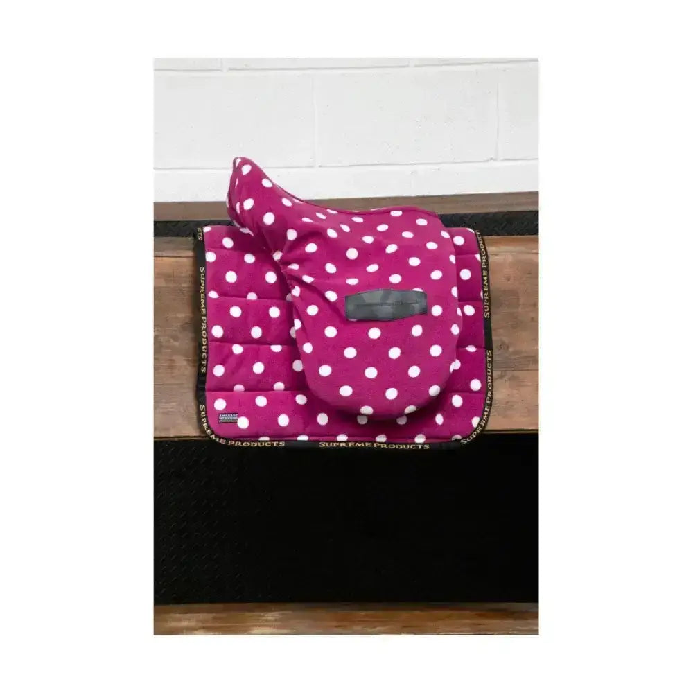 A vibrant magenta fleece saddle pad with white polka dots and supreme products dotty branding on black border