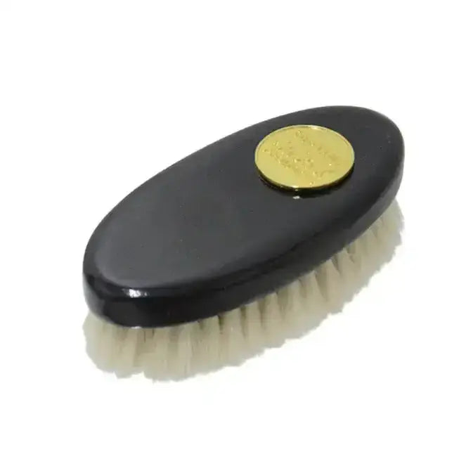 Black oval supreme products perfection goats hair face brush with gold emblem and white bristles for smooth application