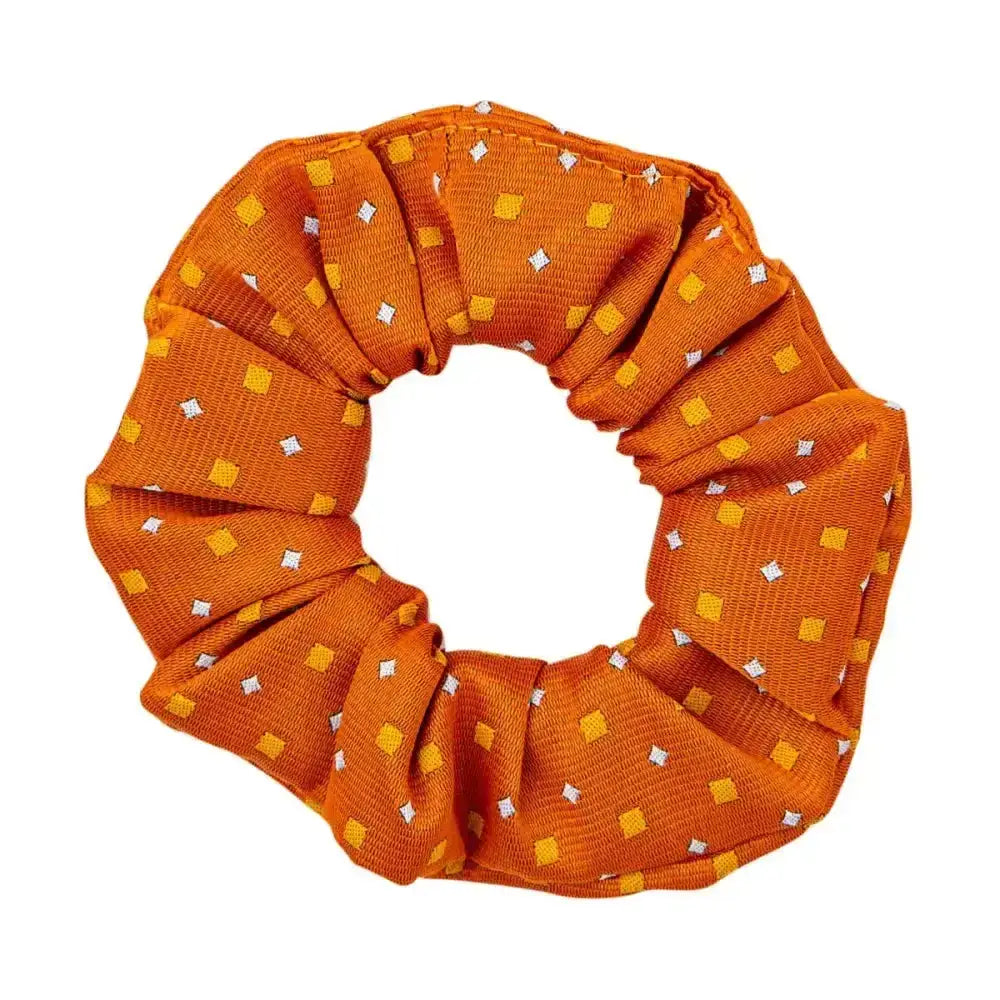 A vibrant orange fabric hair scrunchie with yellow and white squares perfect for the final touch of ring attire