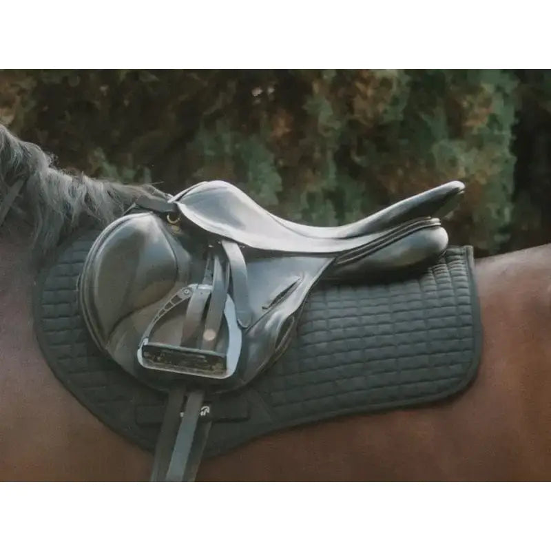 Black leather contact gp saddle with silver hardware resting on a dark quilted saddle pad orange for high wither