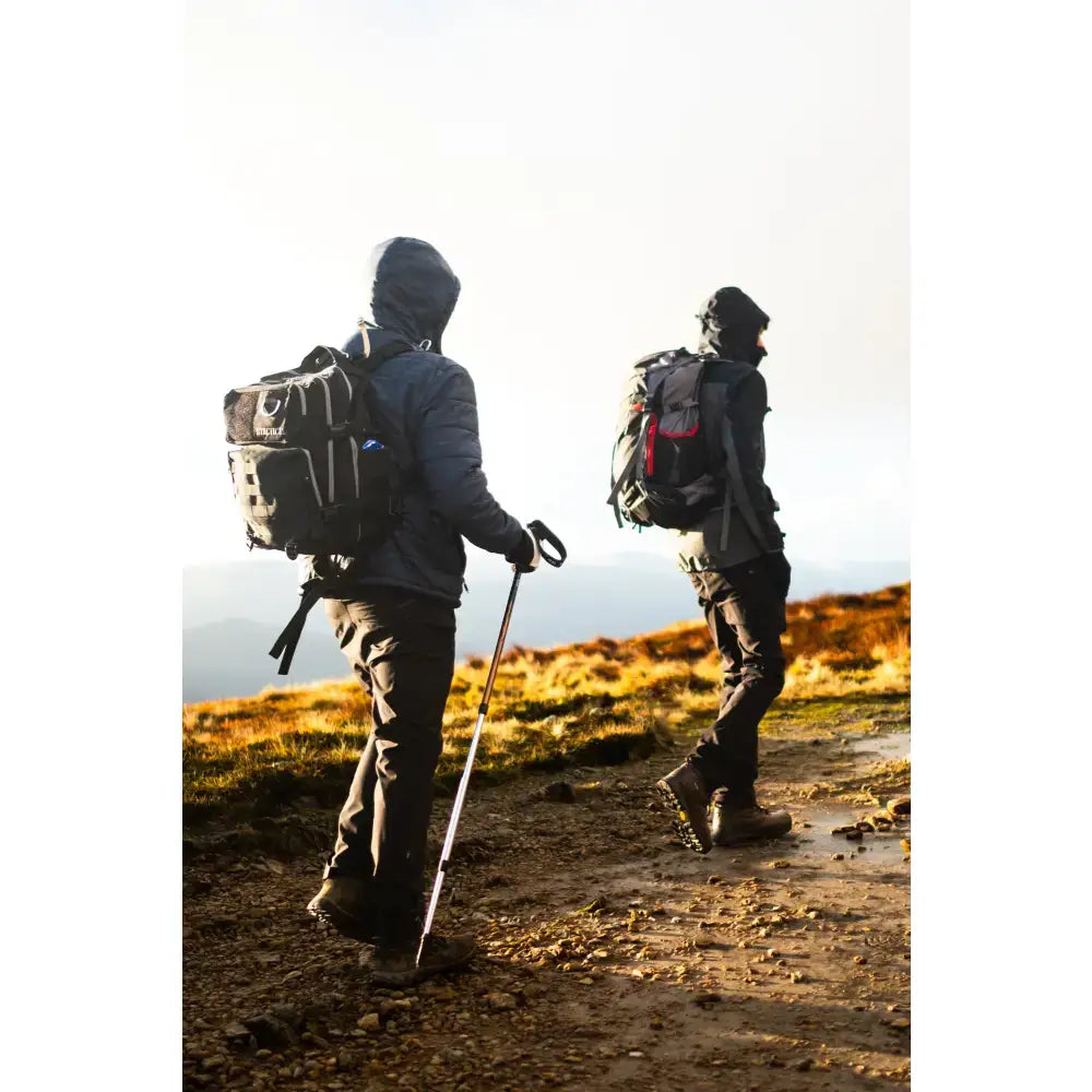 A person wearing the back side of a water resistant 35l btactical backpack black smoke with red accent straps
