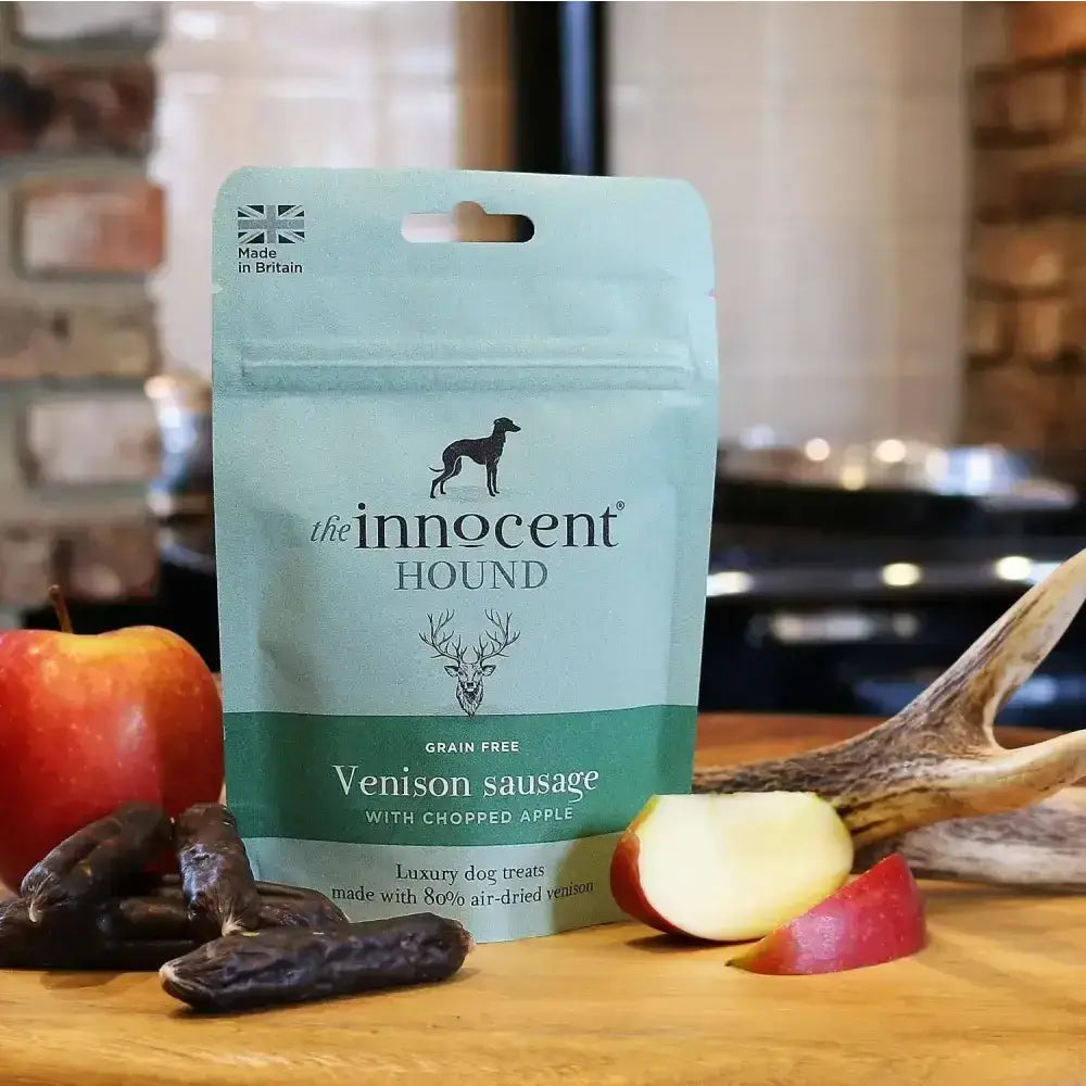 A light teal resealable pouch of innocent hound venison sausage dog treats with chopped apple and black logo