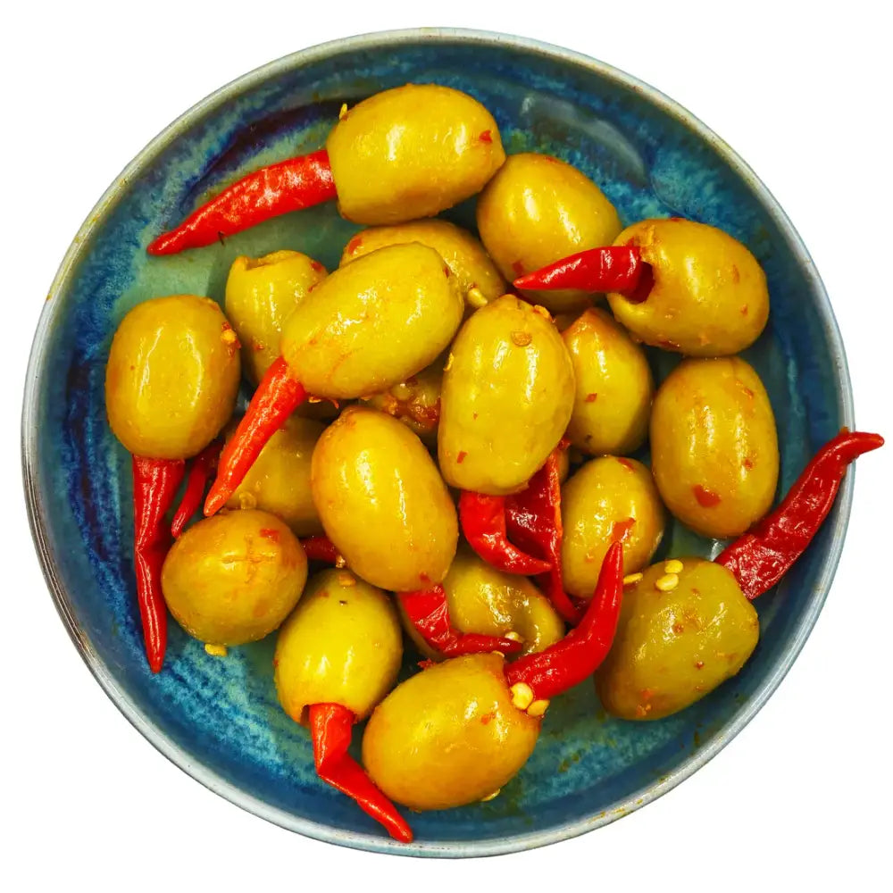 A rustic blue dish filled with vibrant yellow west country hot chilli olives 175g and bright red south devon chilli peppers