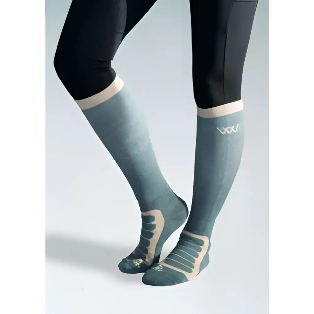 A pair of teal and beige woof wear long bamboo tech riding socks with textured knit and reinforced arch support panels