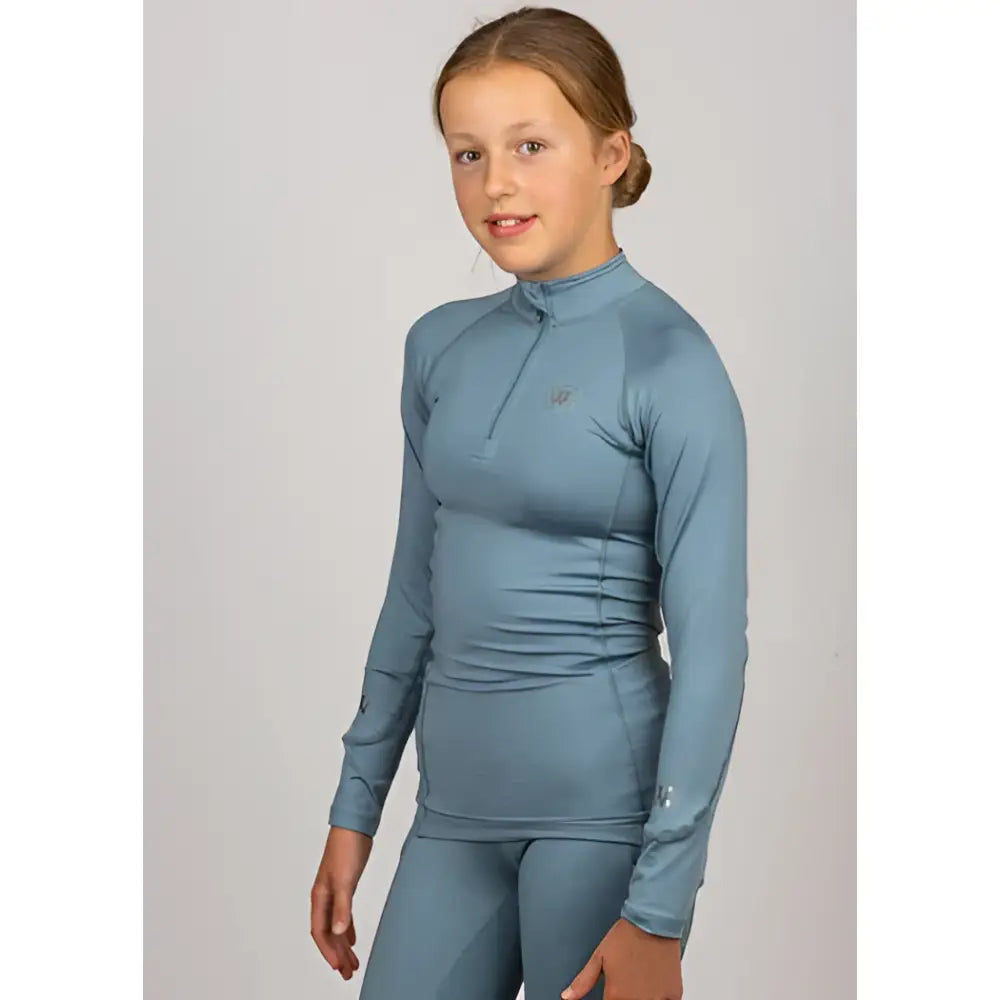 A girl wearing a light blue woof wear young rider tech shirt with ruched iflex fabric and matching leggings