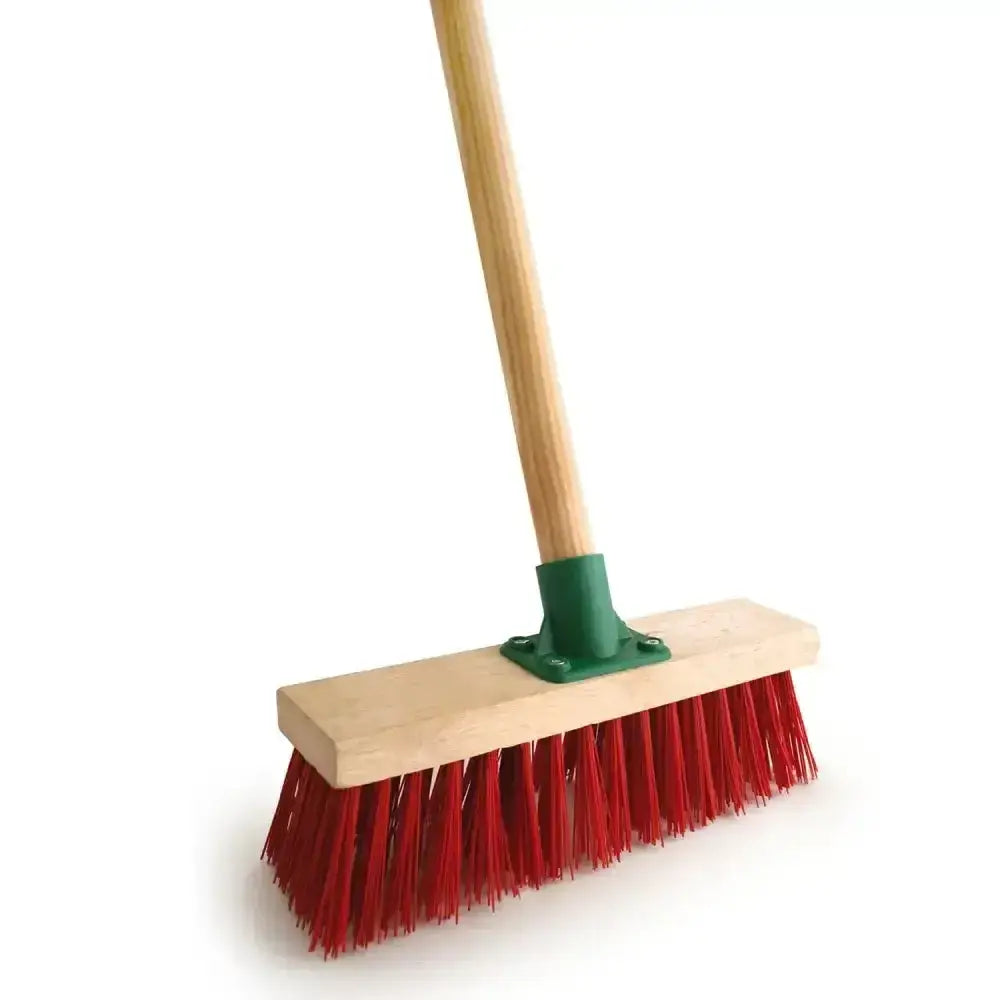 Yard broom fitted with red pvc bristles wooden handle and green metal ferrule for outdoor cleaning tasks