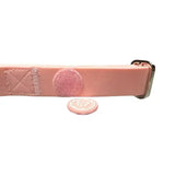 A soft pastel pink pvc btactical dog collar with a silver buckle and matching circular tag for stylish pups