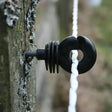 Black plastic rope guide with ring and spiral design on tree bark for agrifence maxicord braided rope smooth contact surface