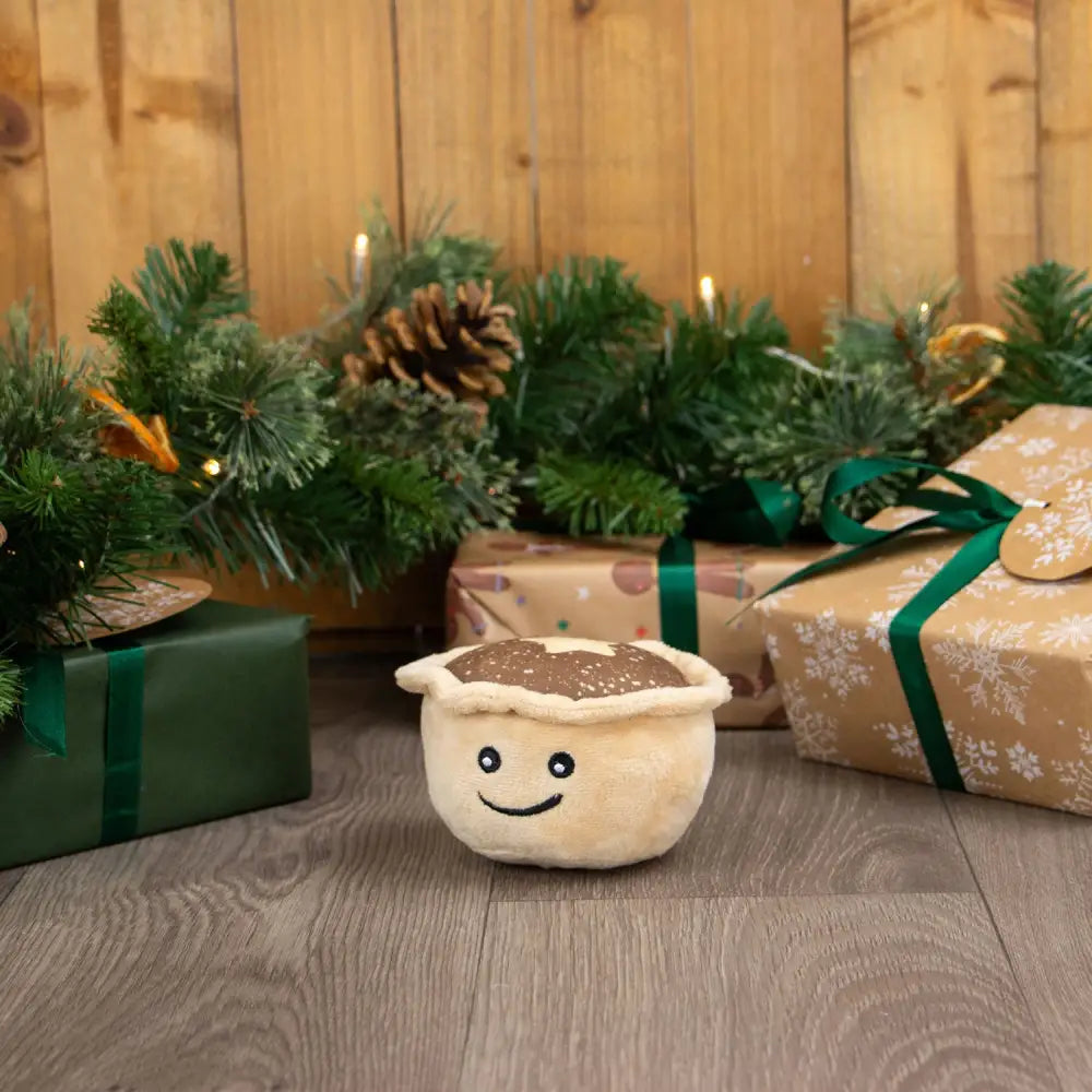 A plush cream-colored ancol matty mince pie toy with a brown textured top and embroidered facial features