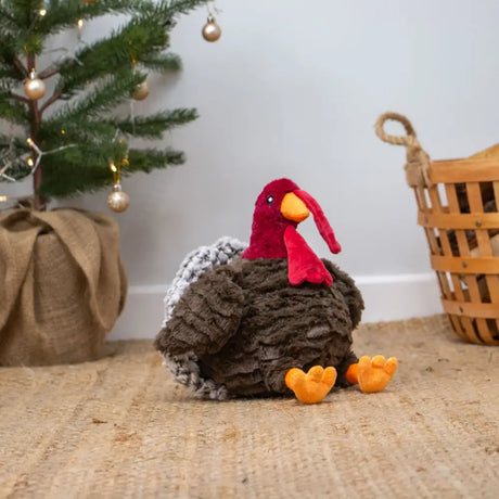 A plush ancol tina turkey toy with a red head orange beak and feet and a brown textured body with gray feathers