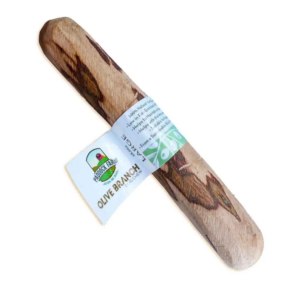 Natural olive wood dog chew toy with light brown and dark streaks wrapped in white label from antos origins olive branch dog
