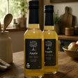 Two 250ml bottles of organic apple cider vinegar with black labels and silver tree logos by broomhill farm co filled with golden liquid