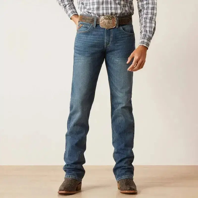 Blue denim ariat mens slim ezra straight jean with classic straight-leg cut paired with plaid shirt and cowboy boots
