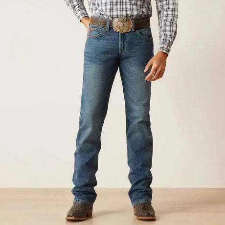 Blue denim ariat mens slim ezra straight jean with classic straight-leg cut paired with plaid shirt and cowboy boots