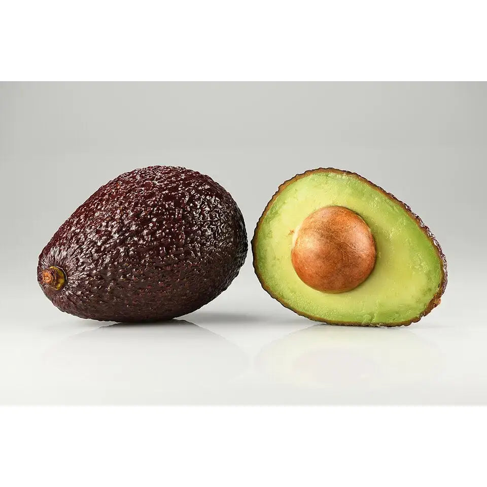 A ripe dark purple avocado with textured skin sits next to its half showing creamy green flesh and a brown seed for equestrian supplies snack
