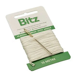 A bitz plaiting card with white plaiting thread and a gold needle in green and cream cardboard packaging