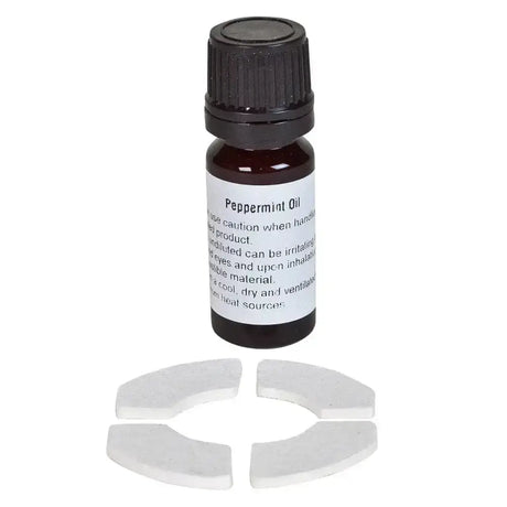Dark amber glass bottle with black cap labeled peppermint oil next to white ceramic pieces in bizzy horse aromatherapy kit
