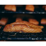 Grilled blakewell smokehouse superior devon hot smoked salmon fillet with golden-brown char on black grill grate