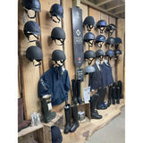Black charles owen equestrian helmet on wooden wall rack for booking a fitting appointment with horses in mind