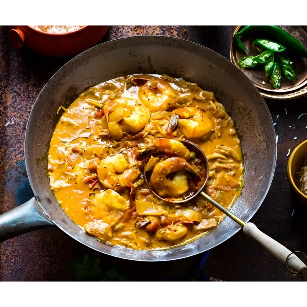 Rich golden-orange shrimp curry simmering in a cast iron skillet from boom kitchen ayubowan sri lankan recipe kit