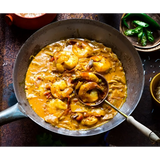 Rich golden-orange shrimp curry simmering in a cast iron skillet from boom kitchen ayubowan sri lankan recipe kit
