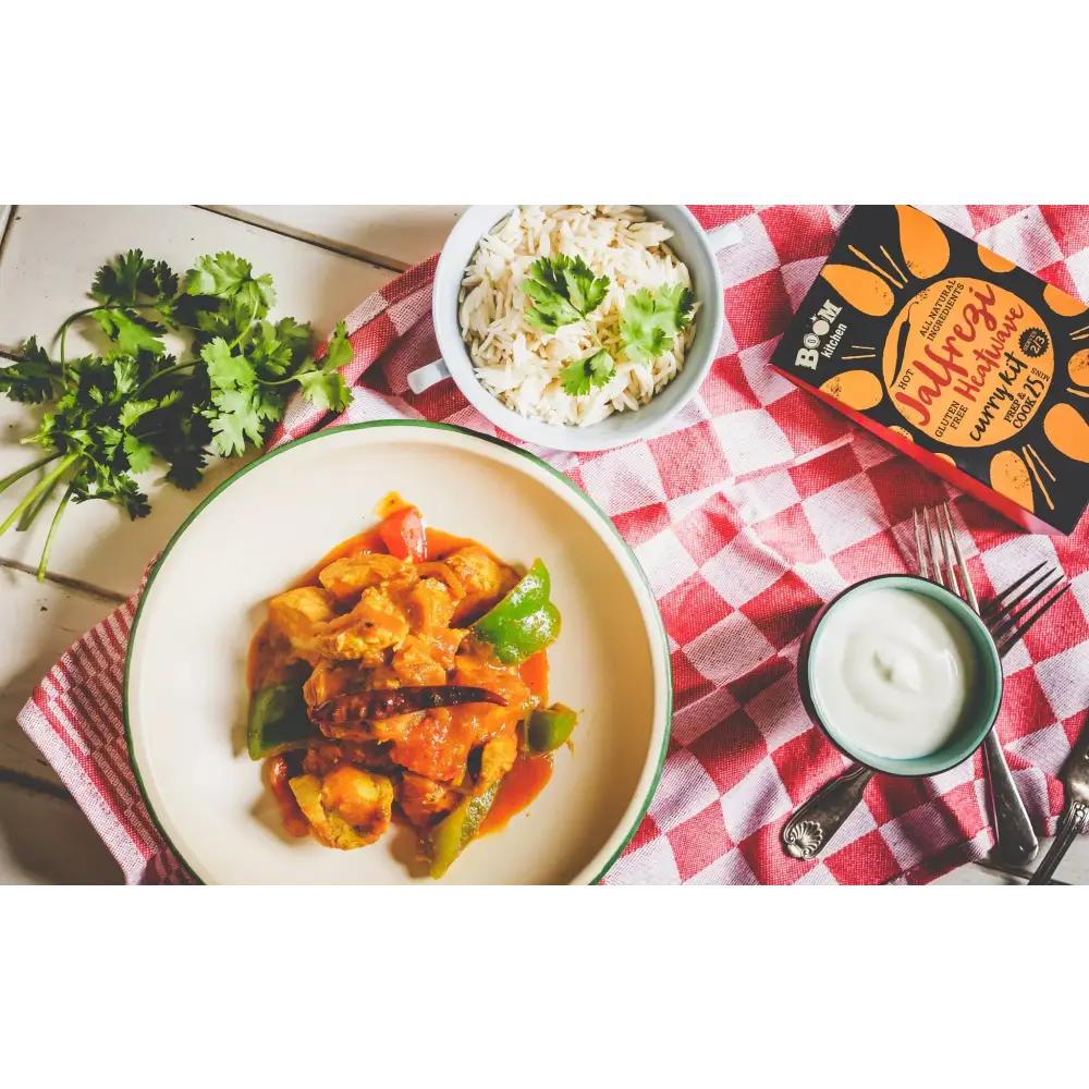 A vibrant orange and green curry in a white bowl with green rim from boom kitchen jalfrezi heatwave kit