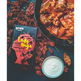 A vibrant red and black boom kitchen lady naga vindaloo curry kit box with bold yellow lettering and stylized design