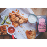 A vibrant orange boom kitchen tikka tarka curry on skewers with lime wedges yogurt dip and red-handled sauce cup