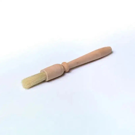 Light-colored wooden handled clipper brush with natural bristles for applying borstiq hoof oil