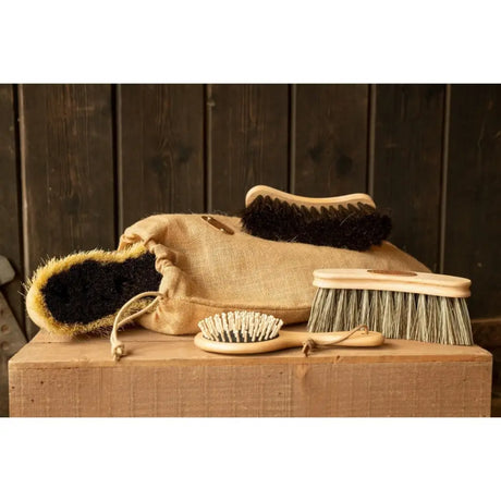 Set of natural wood-handled borstiq show day body brushes with black white and green bristles in a burlap sack perfect for horse grooming combs