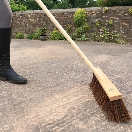 A borstiq wide bassine broom with a sturdy natural wood handle and dense dark brown bristles for farm use