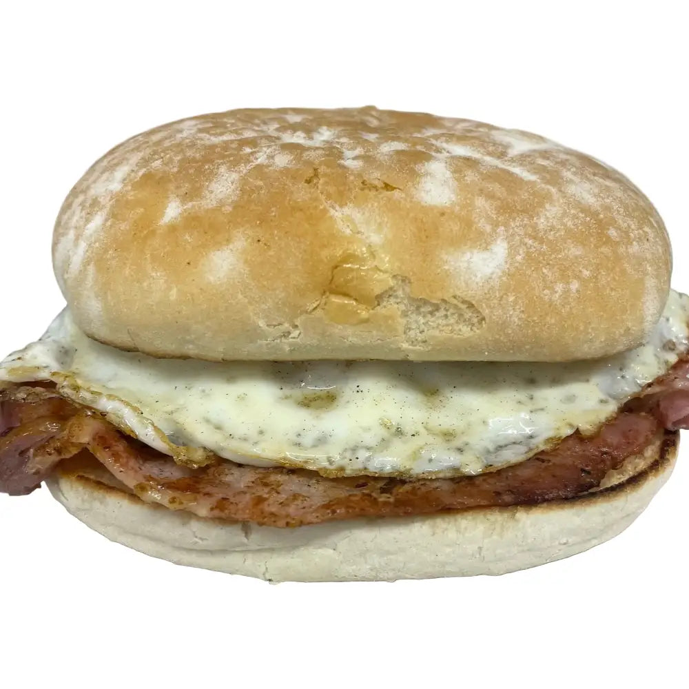 Golden-brown breakfast bap with crispy bacon fried egg and melted white cheese on wheat flour bun