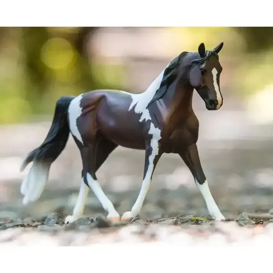 A detailed breyer pinto model horse with dark brown and white paint pattern and black mane and tail for equestrian fans