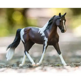 A detailed breyer pinto model horse with dark brown and white paint pattern and black mane and tail for equestrian fans
