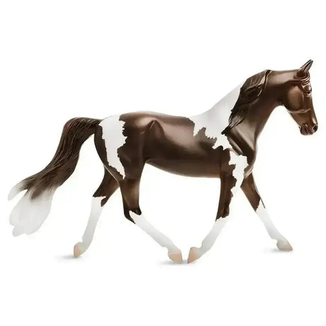 A glossy breyer pinto horse figurine in brown and white pinto-colored horses style with detailed mane and hooves