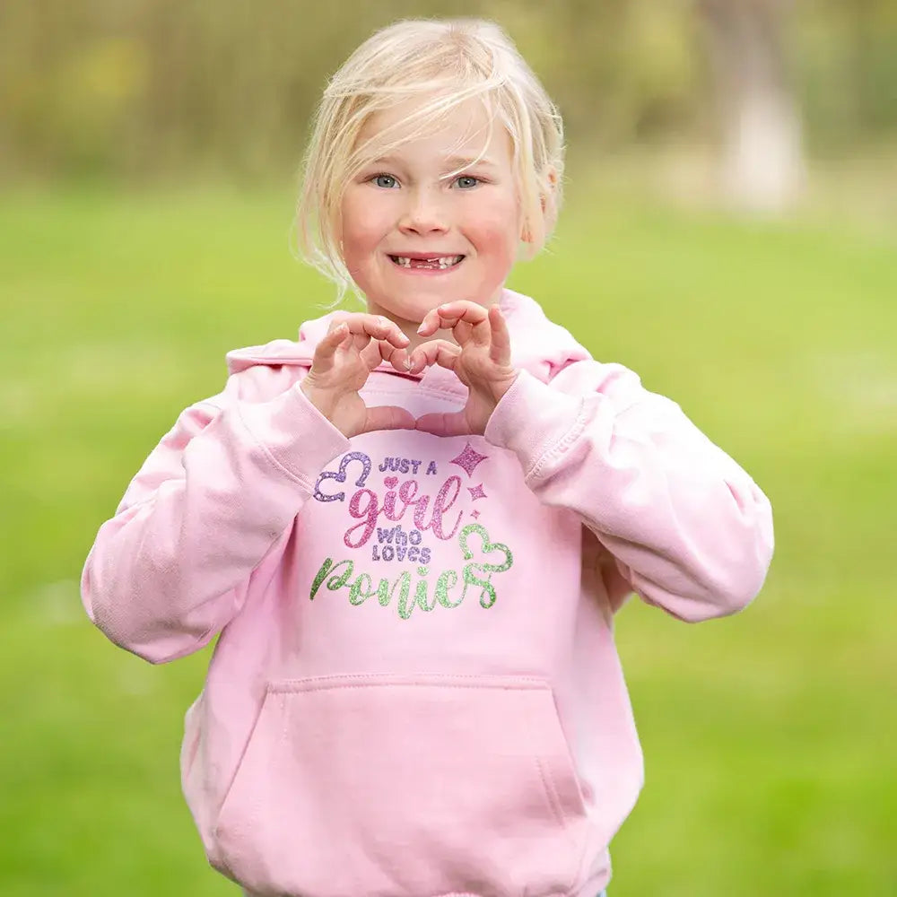 Young child in pink sweatshirt making heart shape for British Country Collection hoodie