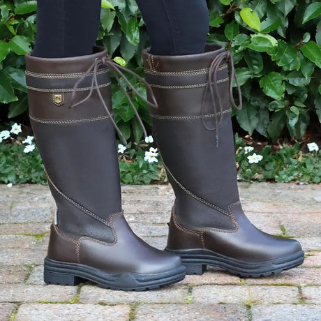 Brown leather riding boots with tan stitching and a small gold logo on the side.