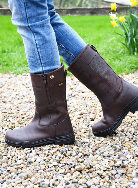Brown leather riding boots with a zipper on the side and a small gold logo near the top.