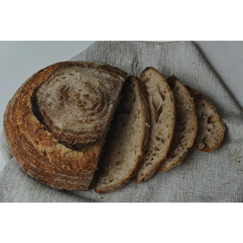 A rustic brown sliced sourdough rise bakery loaf with a dark flour-dusted crust and airy slow proofed interior