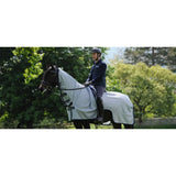 White horse wearing a bucas buzz off two-part mesh rug with black straps designed for sweet itch protection
