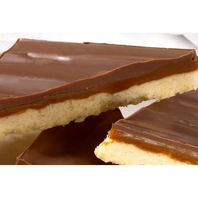 A caramel shortcake slice with glossy dark chocolate topping over caramel and golden shortbread in airtight container