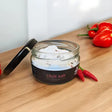A glass jar of white crystalline chilli salt mixed with red pepper flakes from broomhill farm infused salt collection